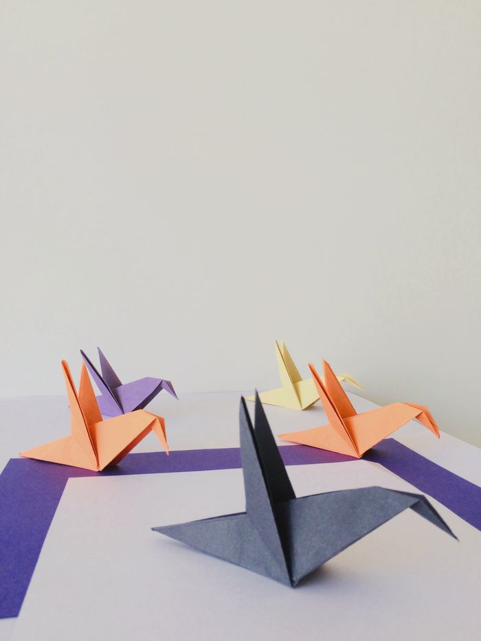 Vibrant origami paper cranes arranged on a geometric background, embodying creativity and precision.
